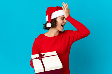 English girl with christmas hat holding a present isolated on blue background has realized something and intending the solution