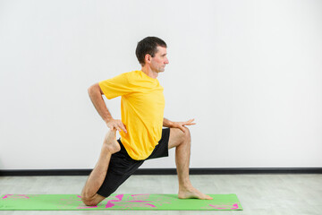 Experienced yogi doing seated forward bend yoga pose in gym. Man practicing yoga. Yogi concept. Side view.