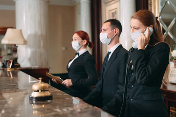 Check in hotel. receptionist at counter in hotel wearing medical masks as precaution against virus....