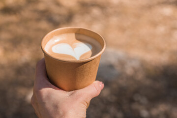 hand holding paper cup of coffee on nature background