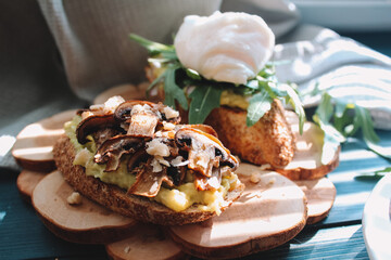 Bruschetta with avocado and mushrooms on a wooden stand.