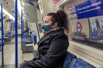 female passenger wearing face covering mask during covid-19 lockdown inside metro train in england...
