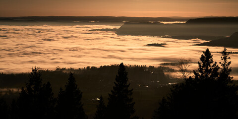 Fototapeta na wymiar The fog is dense and like a lid on top of Oslo, Norway. Clear sky above the fog and it almost loos like clouds. Shot in golden hour and blue hour to get the best light. Shot from Holmenkollen. 