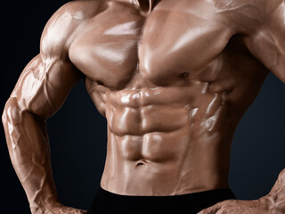 Fototapeta na wymiar Male abdominal muscles, Bodybuilder shows abs, Dark background