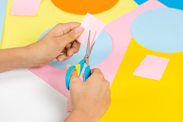 Kid hands cutting colored paper with scissors. Education, learning, paper craft, entertainment at...