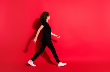 Fototapeta na wymiar Full body profile side photo of young brown hair girl wear casual outfit go walk empty space isolated over red color background