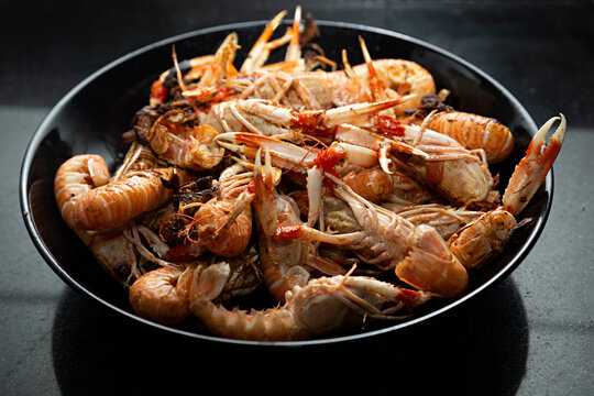 Cigalas fritas en plato negro.