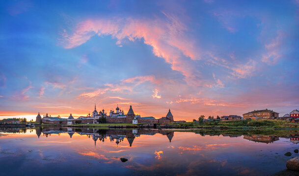 Solovetsky Monastery with a mirror image in the water under a beautiful dawn pink sky © yulenochekk