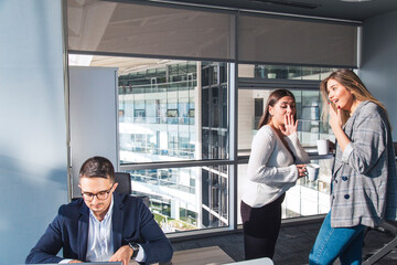 Turkish white collar men is working on desk and there are two colleagues are gossiping at...
