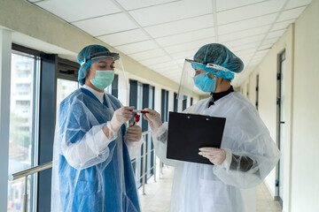Two doctors looking on test tube with blood with positive rezult to coronavirus.