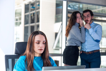 Turkish white collar woman is working on desk and there are two colleagues are gossiping at...