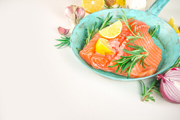 Salmon. Fresh raw salmon fish fillet with cooking ingredients, herbs and lemon in cooking pan, skillet, white background, top view