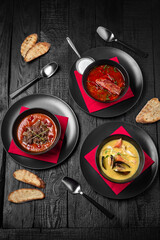 Laid table for a company with an assortment of soups: red borscht or kharcho, seafood cream soup or tom yam, tomato soup with beef or gazpacho. Festive table with delicious food.