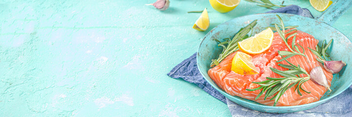 Salmon. Fresh raw salmon fish fillet with cooking ingredients, herbs and lemon in cooking pan, skillet, light blue Turquoise background, top view