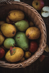 Organic pears and apples in a wicker basket on a rustic table, shot from above