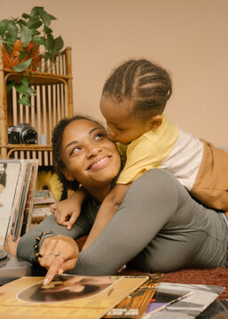Black son giving mom a kiss on the cheek at home