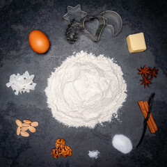 Several Ingredients for Cookies displayed in a circle on a slate plate. A pile of flour in the center. Top shot.