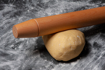 Raw Cookie dough on a slate plate which is covered with flour. A rolling pin is lying on top.