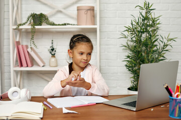tired little child girl pulls out a sheet from a notebook because she made a mistake. hard online...