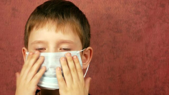 Close-up face of Caucasian preschooler boy putting on protective medical mask, copyspace on the right. Boy Protects Himself From Viruses Selective Focus Shallow Depth Of Field