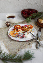 Cheesecakes with cranberries and pine nuts on a gray ceramic plate. Table setting for breakfast.