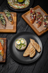 A table set for a group of friends with seafood snacks: bruschetta with salmon and avocado, with herring and tomatoes or cucumbers, forshmak. Festive table with delicious food.