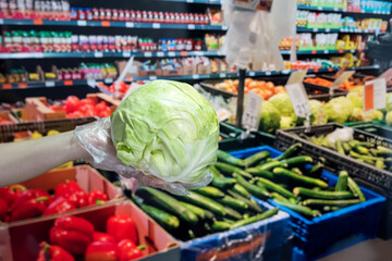 seller in gloves sells fresh vegetables. man gives dollars for groceries in the supermarket.