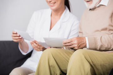 Obraz premium social worker showing photos to aged man on blurred background