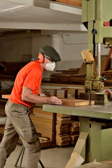 Fototapeta na wymiar carpintero aserrando madera de iroko en la maquina de sierra de cinta