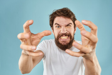 Bearded man in white T-shirt emotions gestures with hands displeased facial expression blue...
