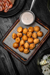 Deep-fried dumplings with garlic sauce on a background of black boards. Festive table with delicious food.