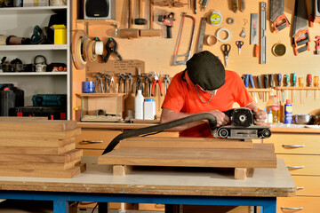 carpintero lijando la madera con una lijadora eléctrica 