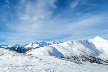 Fototapeta premium A panoramic view on snow capped Alps in Austria, seen from Katschberg Ski Resort in Austria.The slopes are covered with fresh, powder snow. Idyllic winter landscape. Sunny day