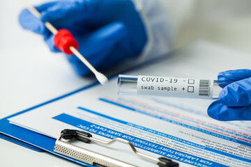 Medical worker holding Coronavirus COVID-19 NP OP swab sample test kit, nasal collection equipment,...