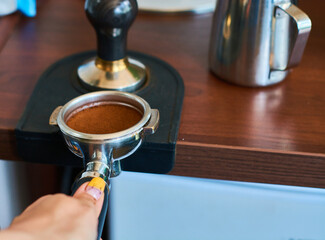 Fototapeta na wymiar The process of temper coffee in holder, making espresso on coffee machine.
