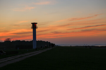Lighthouse silhouette with view of dyke and Baltic Sea at sunset in Heidkate, Germany