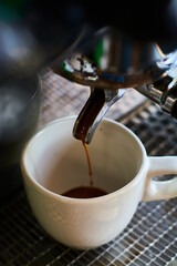 The process of making coffee in white ceramic cup on professional coffee machine.