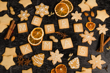 Fototapeta na wymiar christmas food background of gingerbread decorated homewor, icing and spices, delicious homemade christmas cookies on black wooden background, close-up view, cookies, cinnamon, star anise, orange