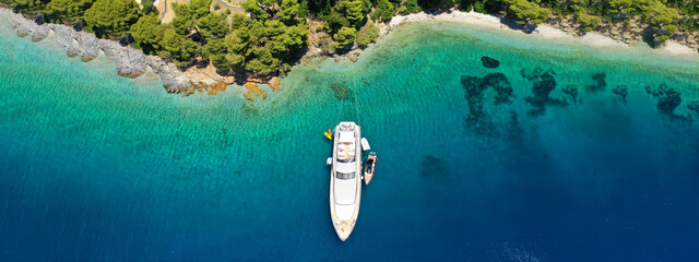Fototapeta na wymiar Aerial drone ultra wide panoramic photo of luxury yacht anchored in tropical exotic island with crystal clear turquoise sea and pine trees