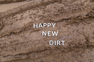 Fototapeta na wymiar the words happy new dirt laid with silver metal letters on wet mud surface