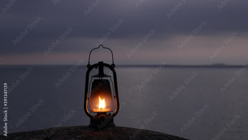 Wall mural beautiful footage of old rustic oil lamp silhouette on a rock. cloudy sunset sky. island in baltic s