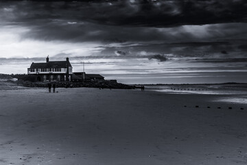Fototapeta na wymiar A solemn walk, early morning at Brancaster Beach, Norfolk