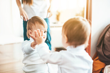 Obraz premium A little child looks in the mirror with his palm on the glass