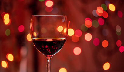 Red wine glass against christmas lights bokeh background