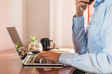 A man working on a laptop with his notebook open and his mobile phone on the table.
