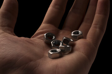screw-nuts in hands on a black background