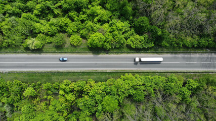 Aerial. Gasoline fuel truck driving by the highway road between green forest. Top view. © Dmytro
