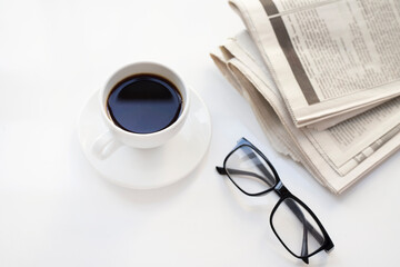 Coffee cup with newspaper and glasses on white table.Take a break.