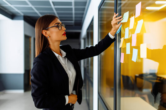 Young businesswoman brainstorming with sticky notes at work in office