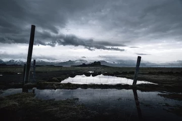 Papier Peint photo Réflexion Dramatic weather over Icelandic farm ruins at dusk reflected in flooded field 